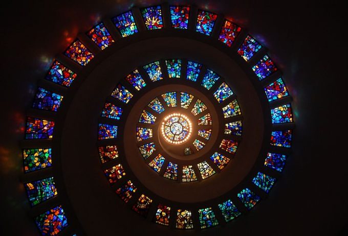 Stain glass windows of different colours spiral upwards.
